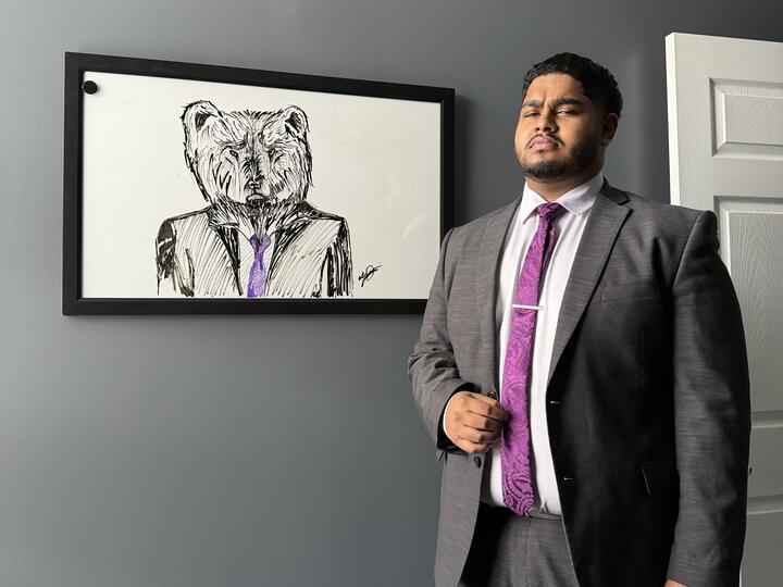 Lorem, Inc team member in a suit beside the company bear artwork